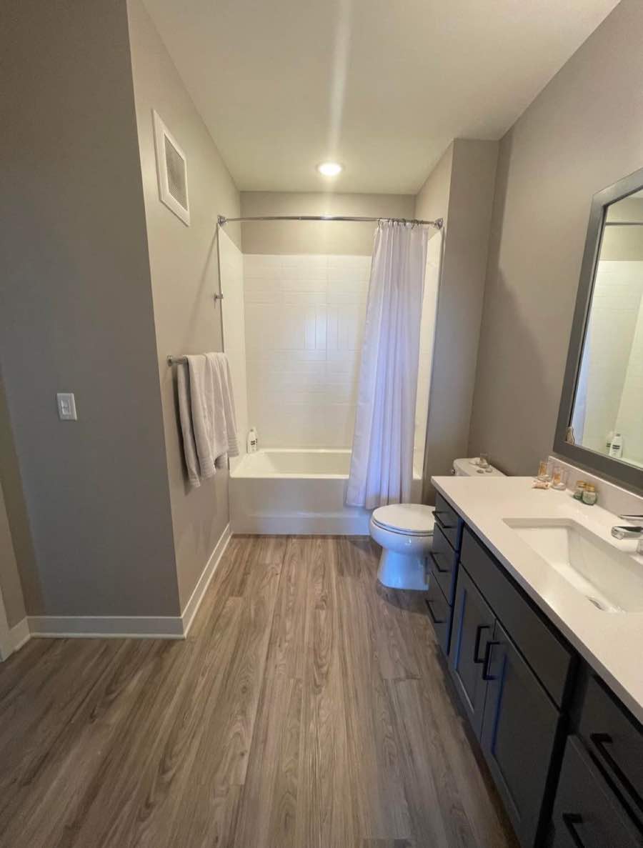 Bathroom with light vanity and wood-look floor