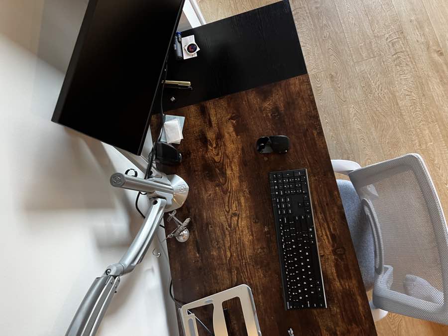 Clean wood office desk with monitor, keyboard, and adjustable monitor arm