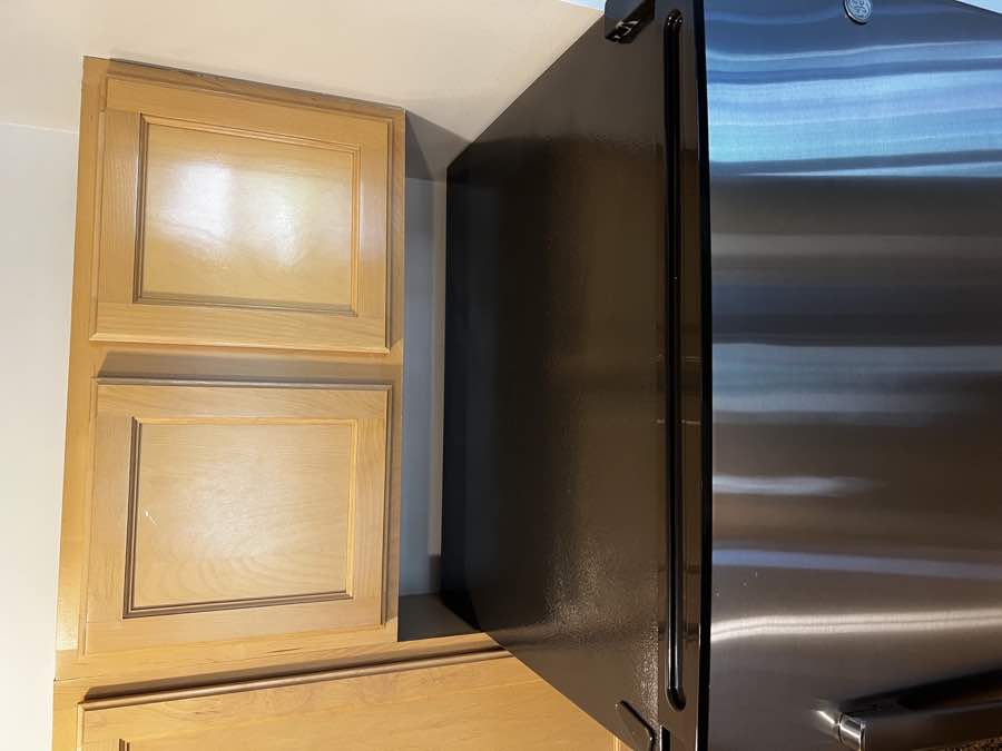 Clean refrigerator top beneath wood cabinets