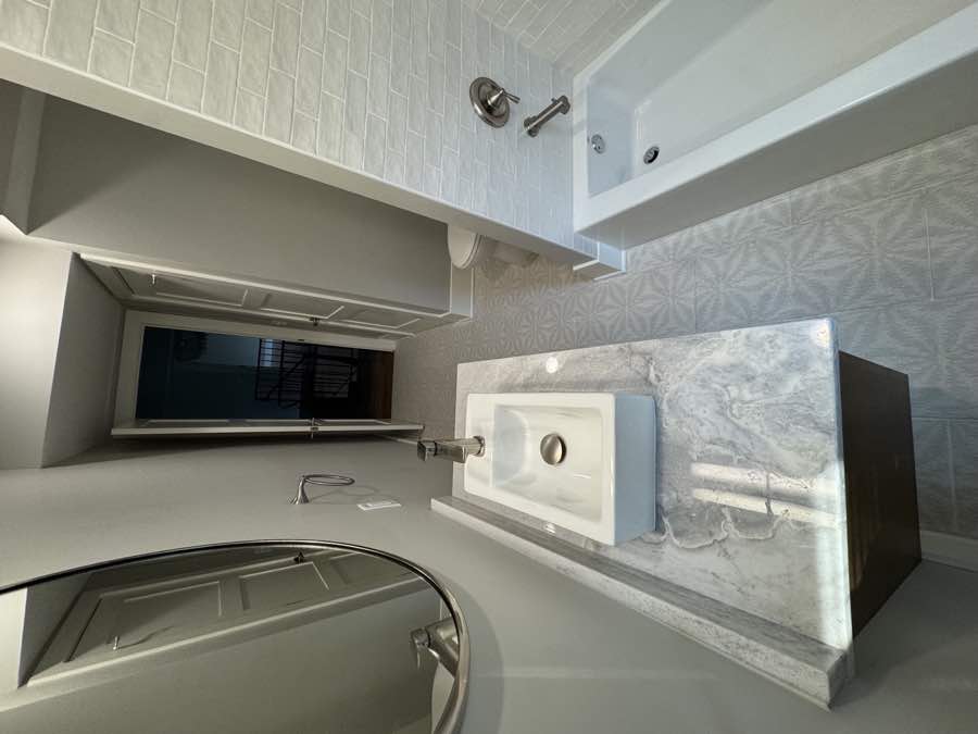 Light bathroom with marble counter and bathtub