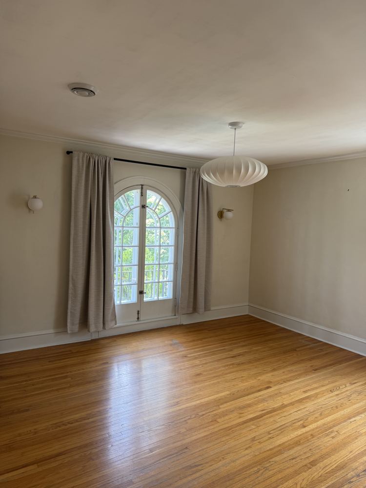 Bright empty room with wood floors and an arched glass door